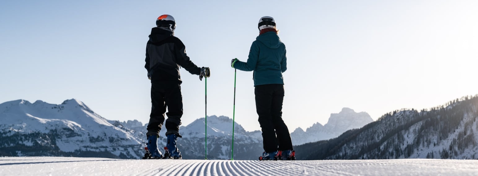 Two skiers on perfectly groomed piste in the Sellaronda looking at the Dolomites